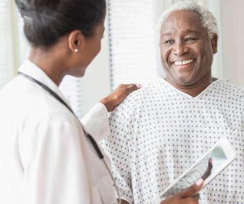 Doctor with digital tablet comforting older man in hospital